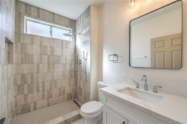 full bathroom featuring toilet, a tile shower, and vanity