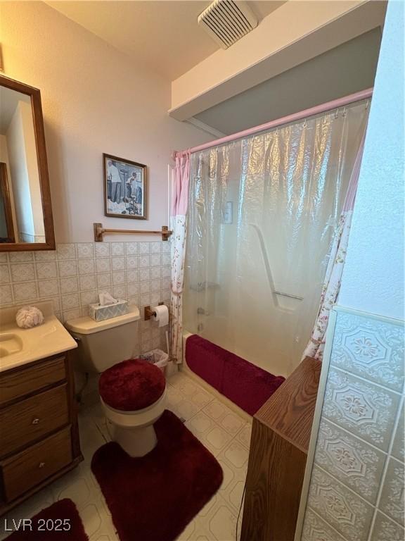 1090E 15th St, Ely, NV 89301 - full bathroom featuring shower / bath combo, toilet, a wainscoted wall, tile walls, and visible vents