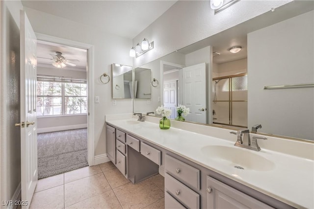 bathroom featuring a sink, double vanity, a ceiling fan, baseboards, and an enclosed shower
