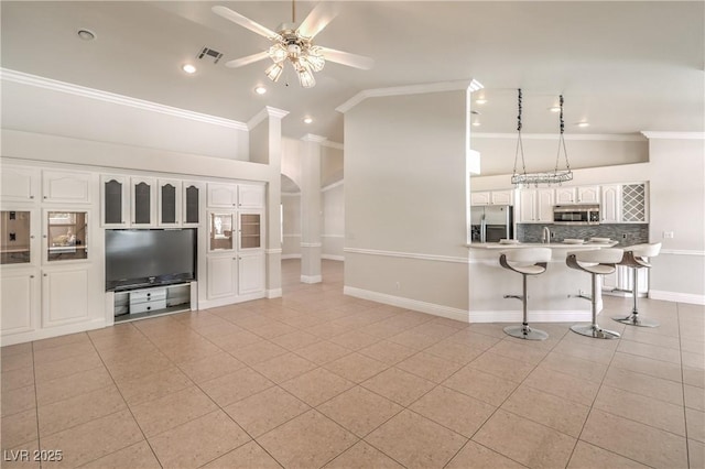 unfurnished living room with ceiling fan, ornamental molding, light tile patterned flooring, and visible vents