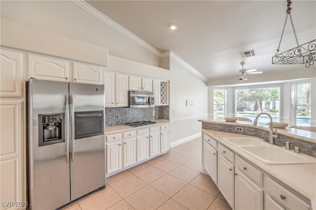 kitchen with decorative backsplash, visible vents, vaulted ceiling, a sink, and stainless steel appliances