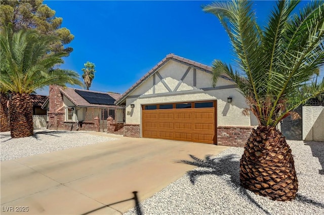 view of front facade with a garage, stucco siding, roof mounted solar panels, concrete driveway, and a tile roof