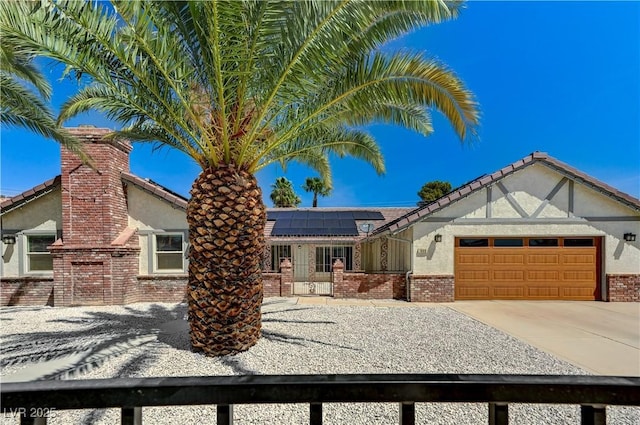 view of front of home featuring stucco siding, brick siding, roof mounted solar panels, and a garage