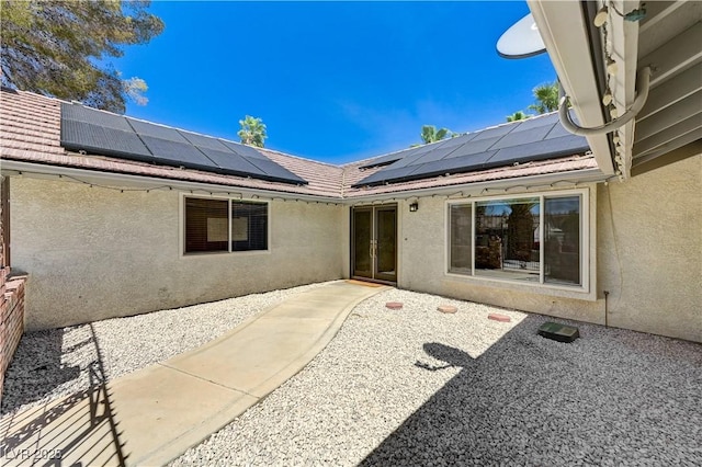 back of property featuring stucco siding, solar panels, and a patio area
