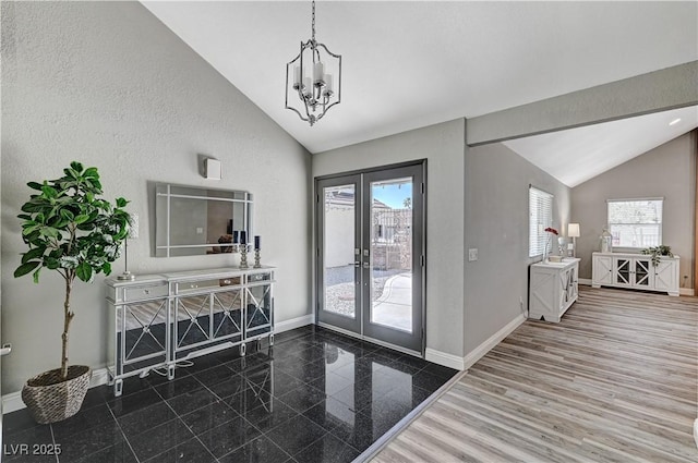 foyer entrance featuring baseboards, lofted ceiling, a chandelier, and french doors
