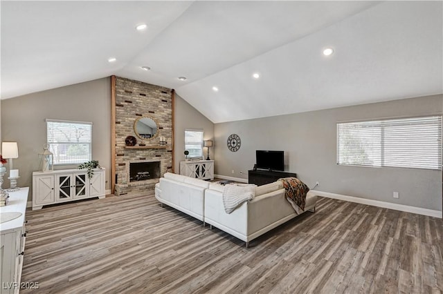 living room featuring baseboards, a fireplace, light wood-type flooring, and lofted ceiling