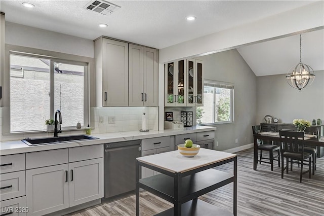 kitchen with gray cabinets, visible vents, stainless steel dishwasher, a sink, and light countertops