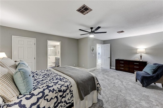 carpeted bedroom featuring baseboards, a ceiling fan, ensuite bath, and visible vents