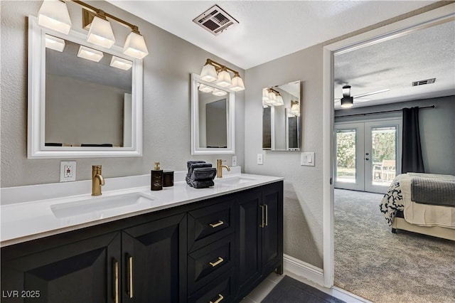 ensuite bathroom with french doors, visible vents, and a sink