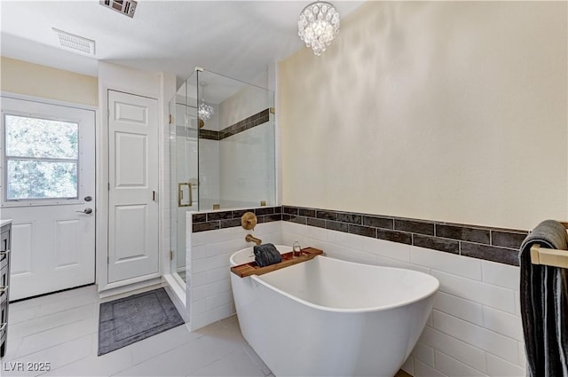 bathroom with visible vents, a freestanding tub, tile walls, tile patterned floors, and a shower stall