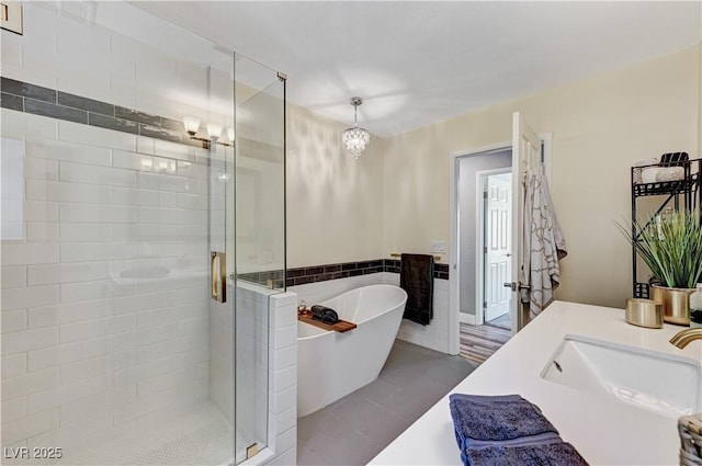 full bathroom featuring vanity, tile patterned flooring, tile walls, a freestanding bath, and a stall shower