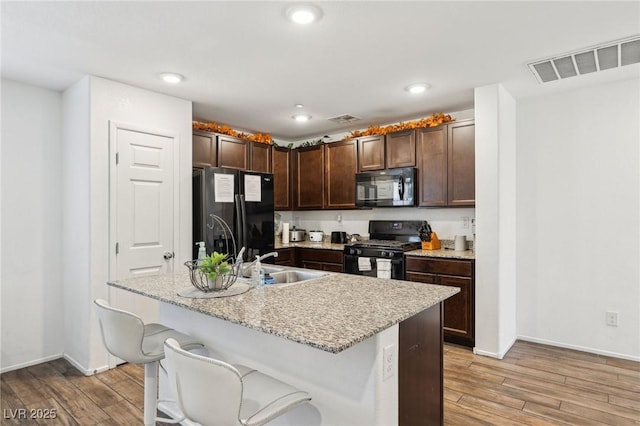 kitchen with visible vents, a sink, light wood-style flooring, and black appliances