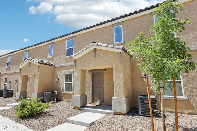 view of front of property with stucco siding, a tile roof, and cooling unit