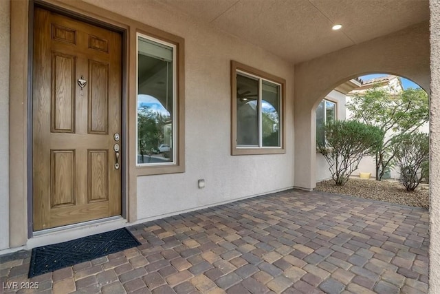 view of exterior entry with a patio area and stucco siding
