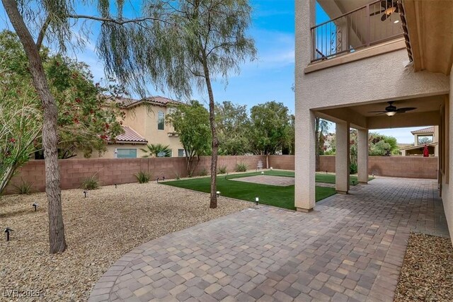 view of patio featuring a fenced backyard, ceiling fan, and a balcony
