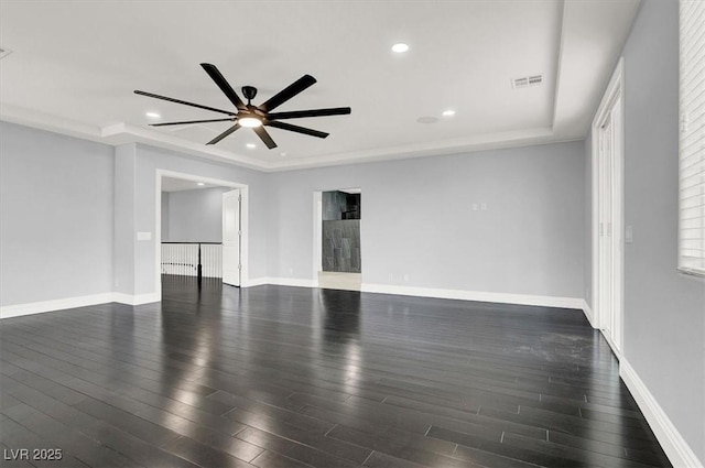 empty room featuring visible vents, baseboards, ceiling fan, and dark wood-style floors