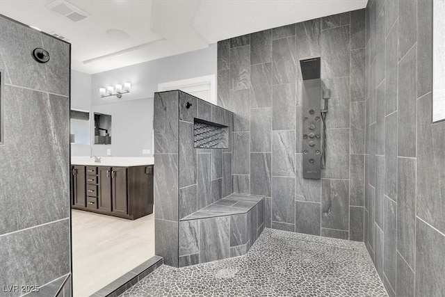 bathroom with vanity, tile walls, tiled shower, and visible vents