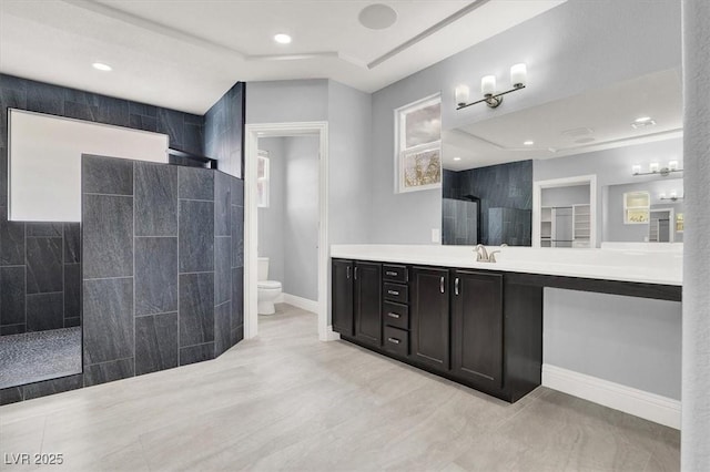 bathroom featuring walk in shower, vanity, toilet, recessed lighting, and baseboards