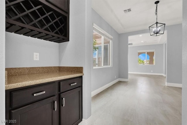 bar with pendant lighting, baseboards, a notable chandelier, and visible vents