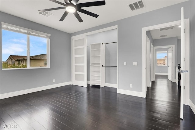 unfurnished bedroom featuring baseboards, wood finished floors, and visible vents