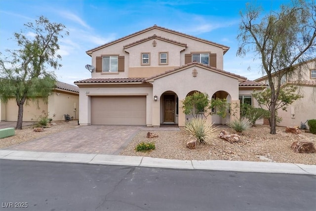 mediterranean / spanish house featuring a garage, stucco siding, driveway, and a tiled roof
