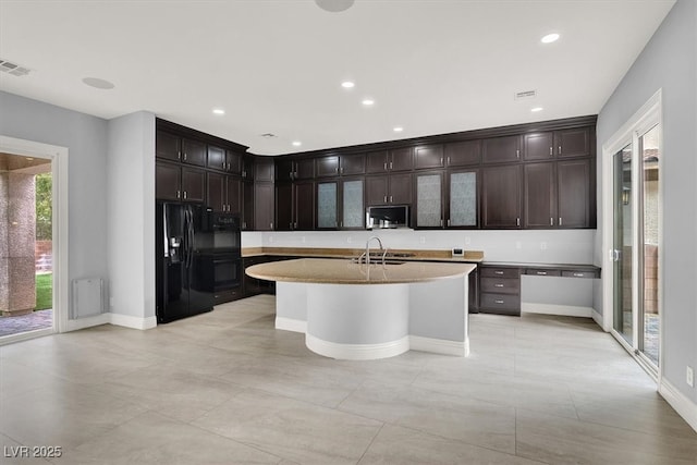 kitchen featuring visible vents, baseboards, light countertops, a sink, and black appliances