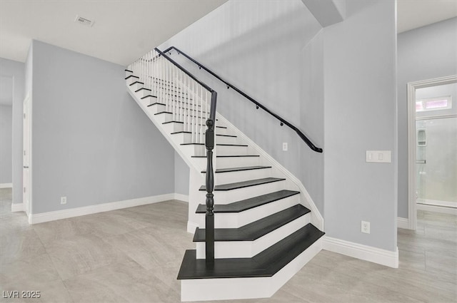 stairway featuring baseboards and visible vents