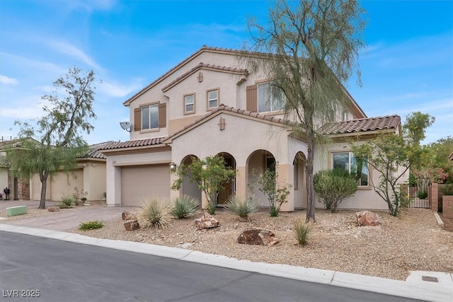 mediterranean / spanish home featuring fence, stucco siding, a tiled roof, an attached garage, and driveway
