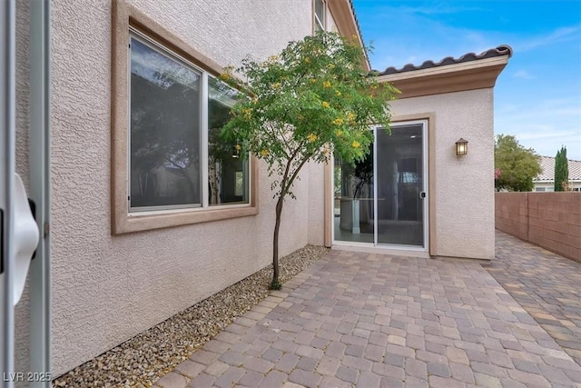 exterior space with fence, a patio area, and stucco siding