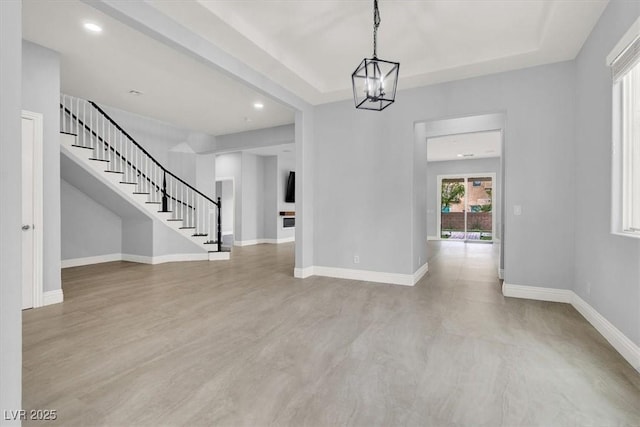 interior space featuring stairs, baseboards, a raised ceiling, a chandelier, and recessed lighting