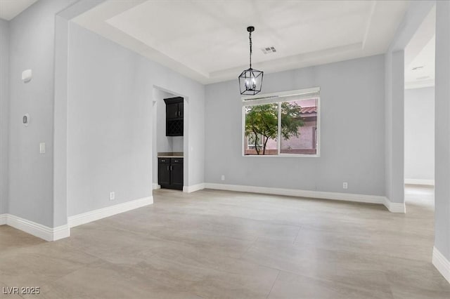 unfurnished dining area with a notable chandelier, visible vents, baseboards, and a raised ceiling