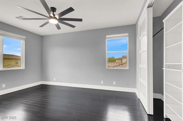 spare room featuring baseboards, dark wood finished floors, ceiling fan, and visible vents