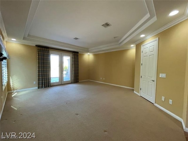 carpeted spare room featuring crown molding, baseboards, a tray ceiling, and visible vents