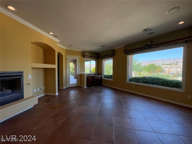 unfurnished living room with crown molding, visible vents, baseboards, dark tile patterned floors, and arched walkways
