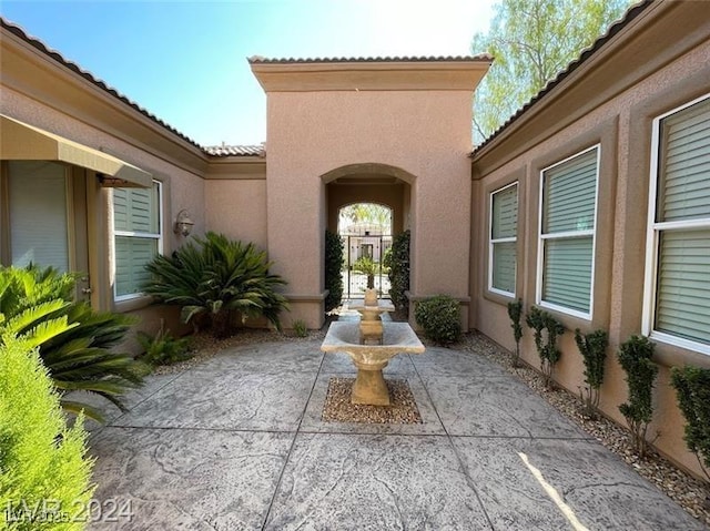 property entrance featuring a patio, stucco siding, and a tile roof