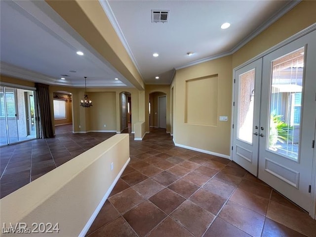 foyer featuring visible vents, ornamental molding, arched walkways, and a chandelier