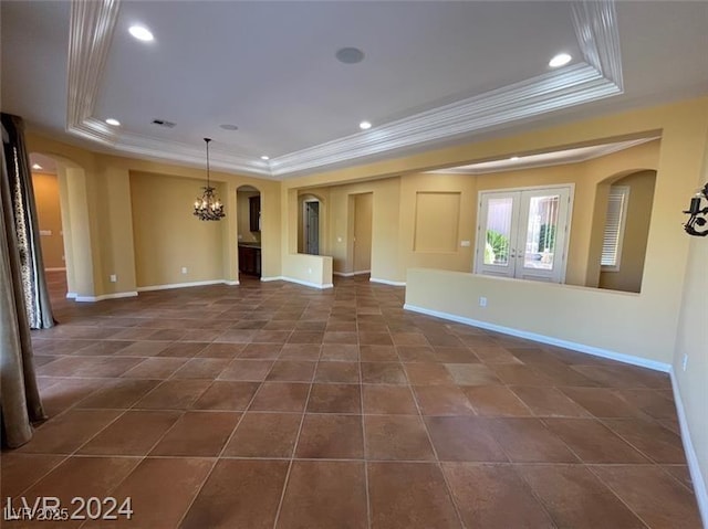 unfurnished living room featuring crown molding, a notable chandelier, arched walkways, baseboards, and a tray ceiling