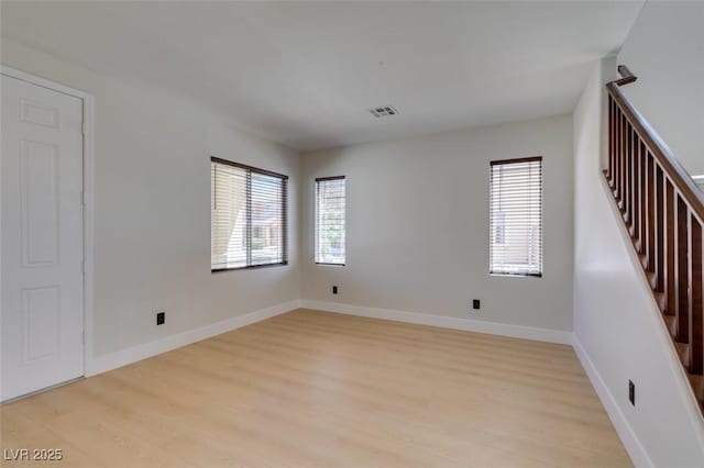 empty room featuring light wood-style floors, baseboards, and visible vents