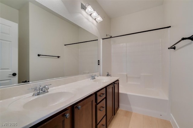 full bathroom featuring a sink, washtub / shower combination, double vanity, and wood finished floors