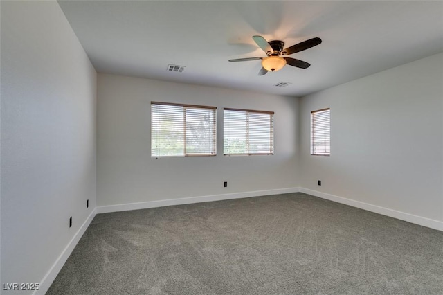 spare room featuring visible vents, baseboards, ceiling fan, and dark colored carpet