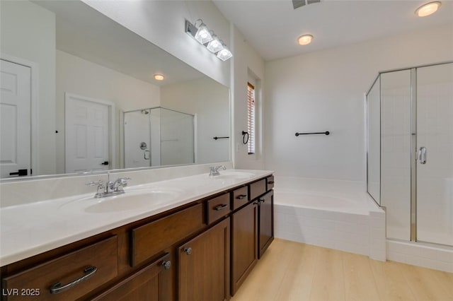 full bath with double vanity, a shower stall, a sink, and a garden tub