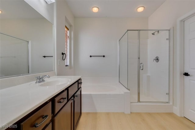 full bath featuring a shower stall, wood finished floors, a garden tub, and vanity