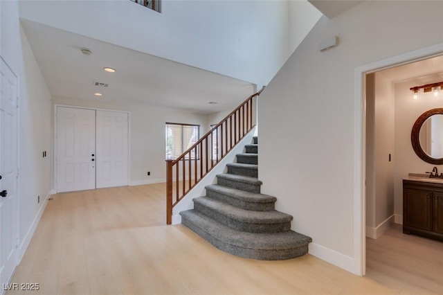 foyer entrance featuring baseboards, stairs, and wood finished floors