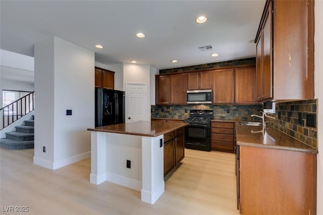 kitchen with light wood-style flooring, baseboards, tasteful backsplash, visible vents, and black appliances