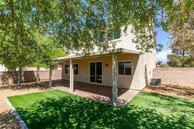 back of house featuring stucco siding, a fenced backyard, central AC unit, a lawn, and a patio