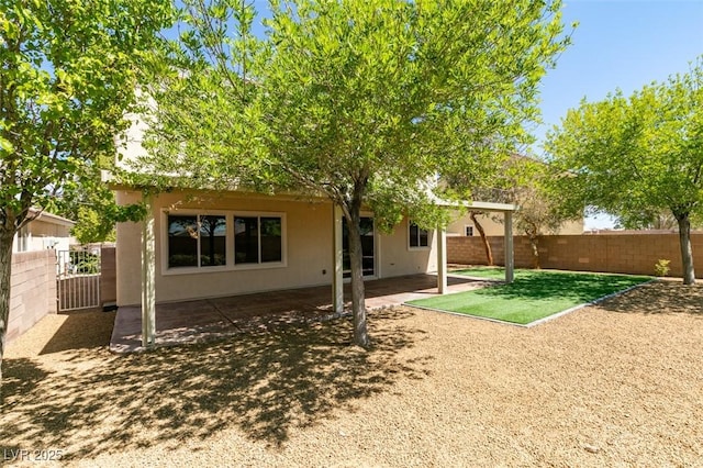 rear view of property with fence private yard, a patio area, and stucco siding