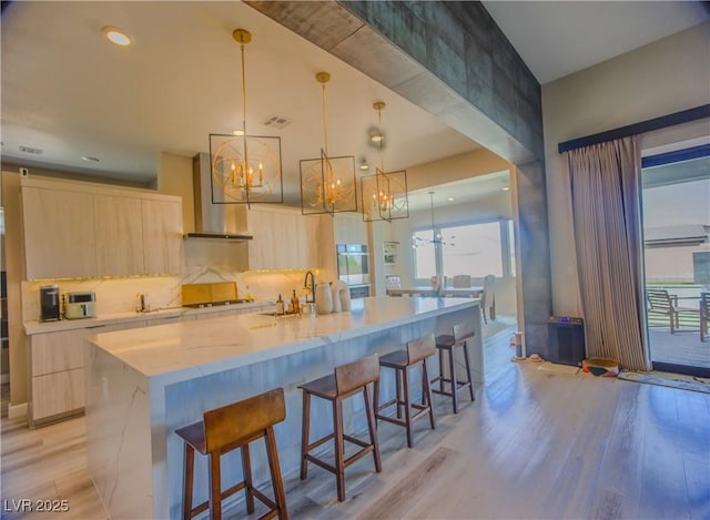 8310 W Camero Ave, Las Vegas, NV 89113 - kitchen with light brown cabinetry, modern cabinets, light wood finished floors, and wall chimney range hood