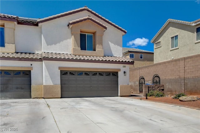 view of front of home featuring a tiled roof, driveway, fence, an attached garage, and stucco siding