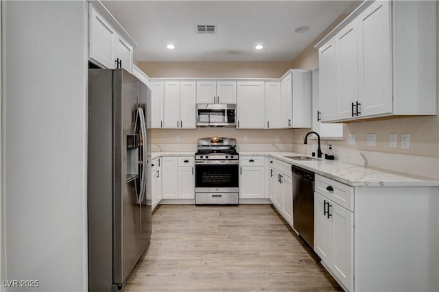kitchen with visible vents, light wood-style flooring, a sink, stainless steel appliances, and white cabinetry