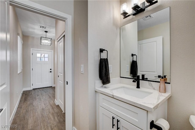 bathroom featuring baseboards, visible vents, wood finished floors, and vanity